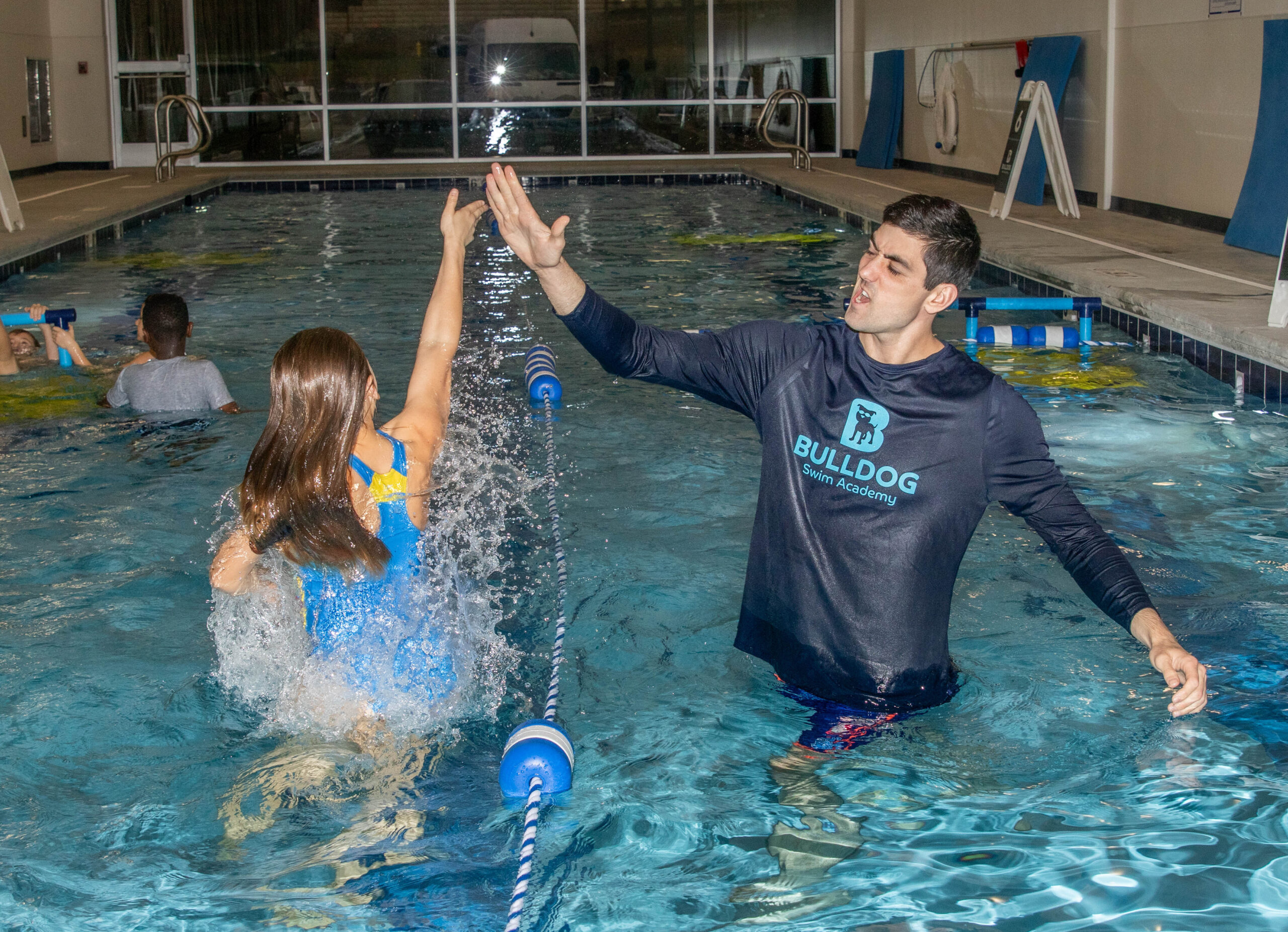 Swim instructor and student high-fiving in the pool